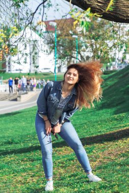 Parkta saçlarıyla oynayan bir kız var.