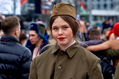 23 Şubat 2019, Minsk Belarus. 23 Şubat bayramı onuruna askeri üniformalı güzel kız sokak partisi sırasında ayakta duruyor.