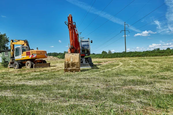 Rote Und Gelbe Leistungsstarke Raupenbagger Stehen Auf Einer Rasenfläche Miete — Stockfoto