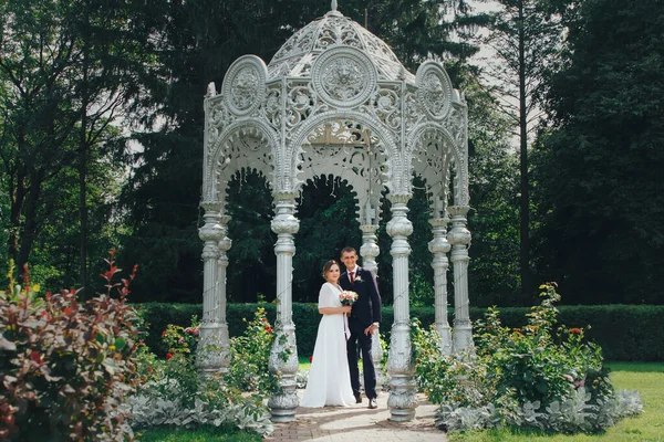 Vista de um casal romântico recém-casado em pé em um gazebo decorativo no parque no dia do casamento — Fotografia de Stock