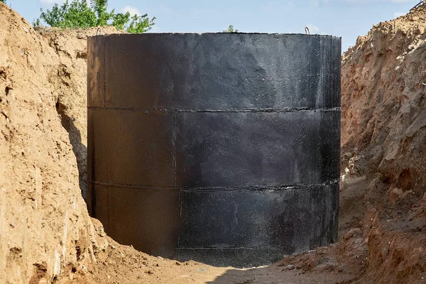 For laying water pipes in a trench with wooden stakes to indicate the direction and height, a concrete well covered with waterproofing mastic was prepared — Stock Photo, Image