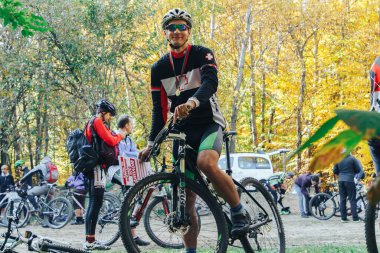 14 Ekim 2018, Minsk, Belarus.2018 Olimpik Kros Kupası XCO Medvezhino 'da bisiklet kaskı takan bir bisikletçi yarış sonrası parkta duruyor.