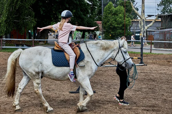 Una ragazza adolescente si sta scaldando, cavalcando un cavallo. Immagine Stock