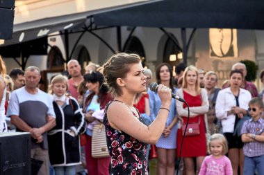 25 Mayıs 2019, Minsk Belarus. Genç, güzel bir aktris tiyatro gösterisinde ağzına tutulan bir mikrofona şarkı söylüyor.