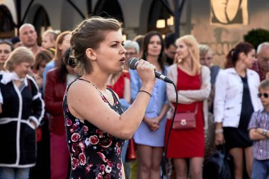 25 Mayıs 2019 Minsk Belarus. Mikrofonlu genç bir kadının kalabalık önünde şarkı söylediği tiyatral bir gösteri.