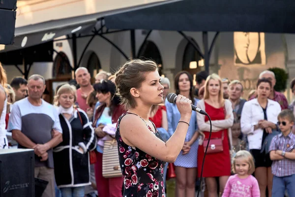25 Mayıs 2019, Minsk Belarus. Genç, güzel bir aktris tiyatro gösterisinde ağzına tutulan bir mikrofona şarkı söylüyor.
