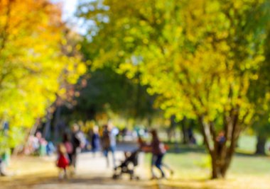 Şehir parkının arka planında gün içindeki insanların bulanık görüntüsü