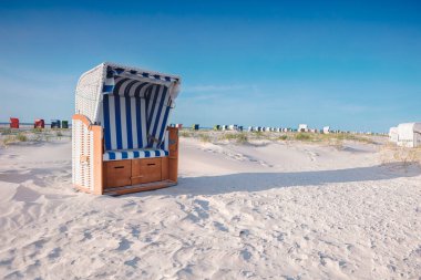 Kuzey Denizi kıyısındaki boş kumsalda birkaç tane hasır plaj sandalyesi var. Tatil köylerinde plaj malzemeleri. Yaz tatili, deniz konseptinde tatil.