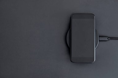 Cep telefonunun endüksiyon kablosuz şarjı. Akıllı telefonun şarj olma açısı yüksek. Modern teknoloji, kablosuz aygıt ve enerji aktarımı.