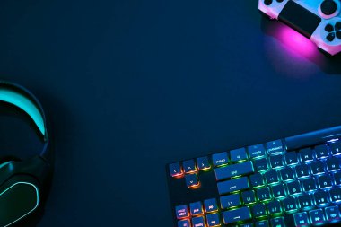 Karanlık masanın üzerinde duran arka ışıklandırılmış oyun aksesuarları. Profesyonel bilgisayar oyunu, esport işi ve online dünya konsepti.