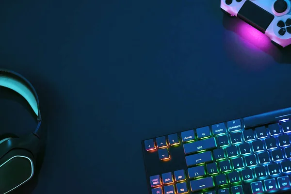 Top down view of backlighted gaming accessories laying on dark desk. Professional computer game playing, esport business and online world concept.