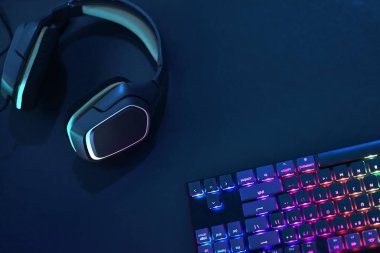 Kulaklıklar, gökkuşağı renklerinin yanında bilgisayar klavyesinin arkasında duruyordu. Profesyonel bilgisayar oyunu, esport işi ve online dünya konsepti.