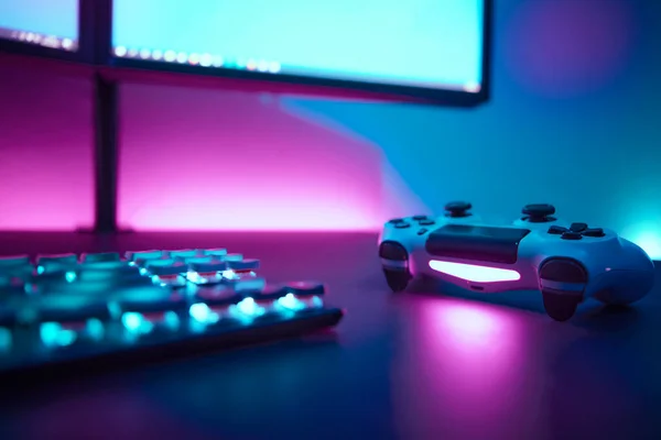 ダークテーブル上のバックライト付きゲームアクセサリーの低角度ビュー 背景にライトブルーとピンクの照明付きの壁 プロのコンピュータゲームプレイ スポーツビジネスとオンライン世界の概念 — ストック写真