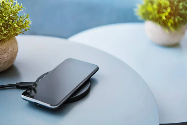 Kablosuz indüktif akıllı telefon pili. Açık mavi arka plana karşı elektronik iletişim cihazı. Modern teknoloji, kablosuz aygıt ve enerji aktarımı.