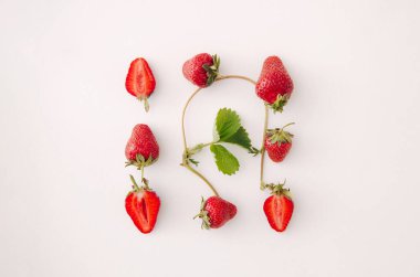 Beyaz arka planda taze kırmızı çilek ve yaprak. Üst manzara, düz uzanma.