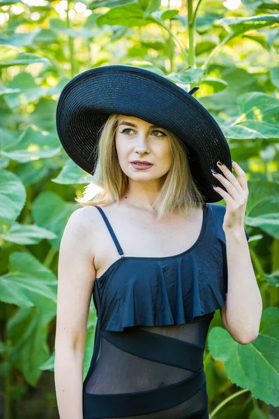 金发碧眼的欧洲姑娘 身穿黑色泳衣 戴着一顶带向日葵的自然帽 — 图库照片