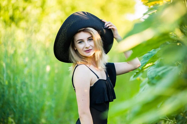 金发碧眼的欧洲姑娘 身穿黑色泳衣 戴着一顶带向日葵的自然帽 — 图库照片