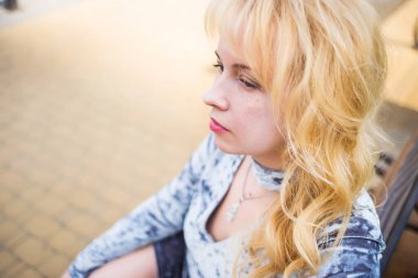 Şehir parkında nehir kenarında poz veren mavi elbiseli sarışın.