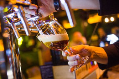 Barmen bardaklara köpüklü bira dolduruyor. Ukrayna 'da restoran.