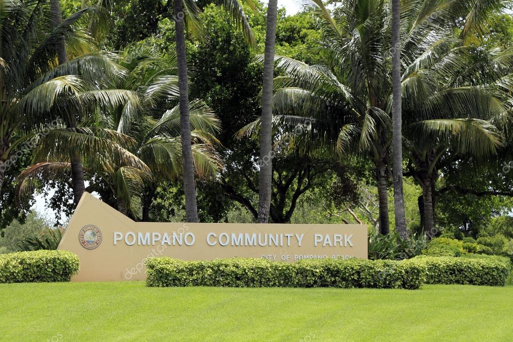 Pompano Beach, FL, USA - June 21, 2014: Large, beige cement sign near the corner of Federal Highway and NE 10th Street. The sign surrounded by bushes, lawn and trees also says City of Pompano Beach twice with Florida added on the city emblem