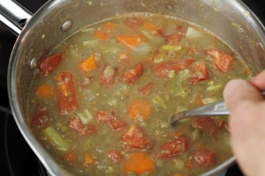 Sıcak mercimek çorbası küçük bir tavada karıştırarak