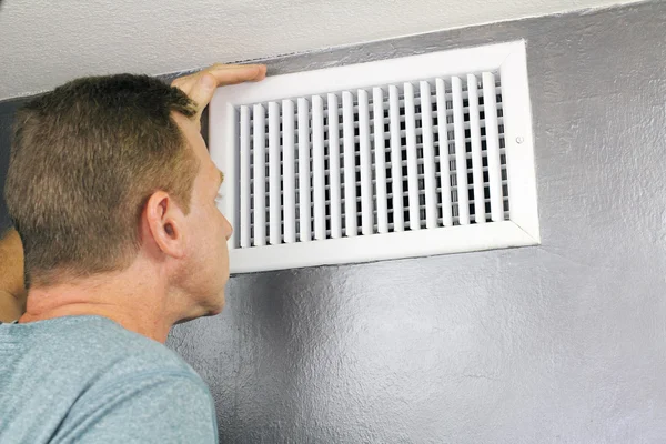 Inspecionando uma ventilação de ar em casa para manutenção — Fotografia de Stock