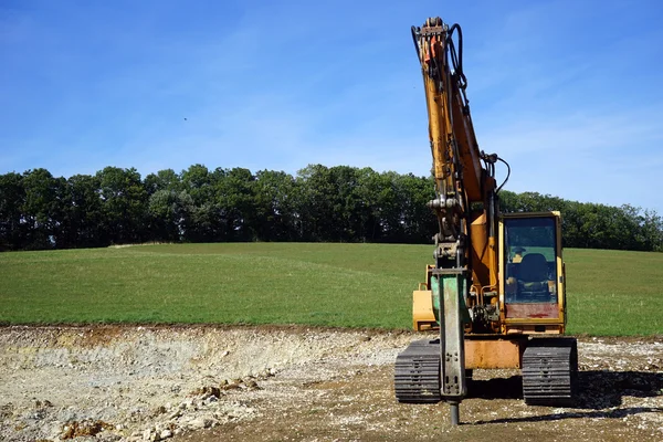 Žlutá buldozer poblíž zelená pole — Stock fotografie