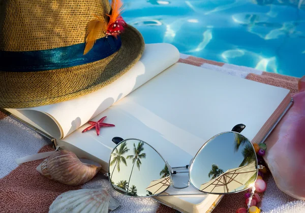 Arte Sombrero de paja, libro y gafas de sol en la playa — Foto de Stock