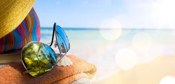 Słomkowy kapelusz, torba i słońce okulary na tropikalnej plaży — Zdjęcie stockowe