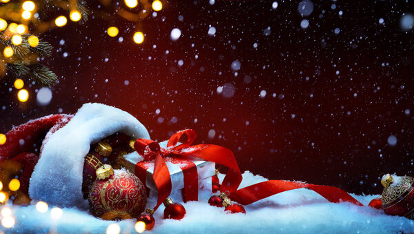 Santa Claus red bag with Christmas balls and gift box on snow