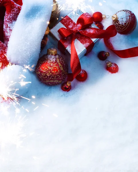 Τέχνη Χριστούγεννα φόντο με ένα κόκκινο στολίδι, κιβώτιο δώρων στο χιόνι — Φωτογραφία Αρχείου