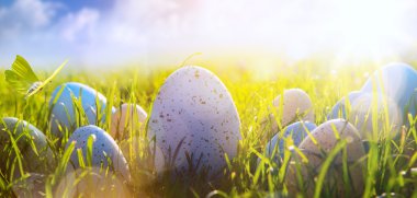 Mavi gökyüzü arka plan üzerinde çim üzerinde sanat renkli Paskalya yortusu yumurta