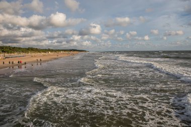 Palanga, Litvanya - 11 Temmuz 2020: İnsanlar Litvanya 'nın Palanga kentinde rüzgarlı bir akşamda Palanga sahilinde yürüyorlar.