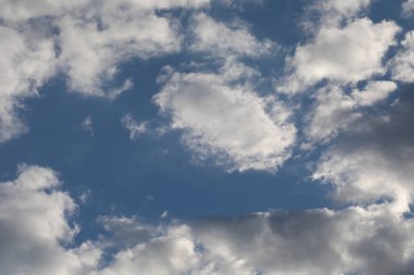 Parlak güneşli bir gün, bulutlu beyaz tüylü kümülüs bulutlarıyla dolu, doğal renkler.