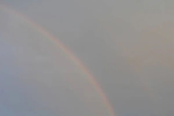 Natural rainbow in the gray overcast sky, atmospheric phenomenon