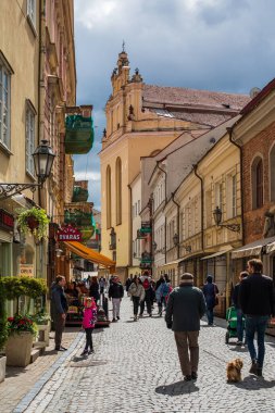 Vilnius, Litvanya - 8 Mayıs 2021: Vilnius 'un en eski ve en gösterişli caddesi olan Pilies Caddesi' nde yürüyen turistler. Aziz John Kilisesi sağda görünüyor..