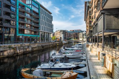 Oslo, Norveç - 16 Temmuz 2025: Günümüz konut ve ofis binaları güneşli bir yaz öğleden sonrasında rıhtımda demirlemiş teknelerle Aker Brygge rıhtımında hizmete girerler..