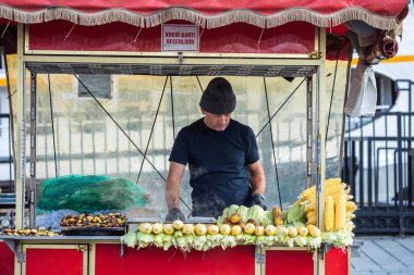 İstanbul, Türkiye - 5 Ekim 2025: Arabasında kestane ve mısır satan bir satıcı, özellikle sonbaharda popüler olan ikonik sokak yemekleri..