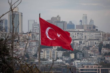 İstanbul, Türkiye - 4 Ekim 2025: Türkiye 'nin ulusal bayrağı, bulutlu bir sonbahar gününde ülkenin en büyük kenti olan İstanbul' un genişleyen kenti üzerinde dalgalanıyor.