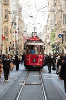 İstanbul, Türkiye - 6 Ekim 2025: Tarihi kırmızı Taksim-Tünel tramvayı (Nostalji Tramvayı), Beyoğlu 'nda, aydınlık ve güneşli bir sonbahar gününde, kalabalık yaya geçidinde ilerliyor..