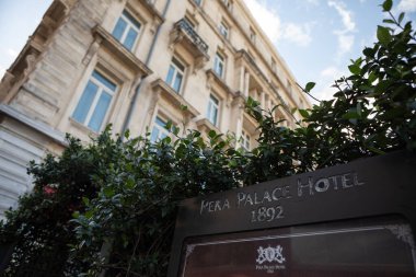 İstanbul, Türkiye - 6 Ekim 2025: Tarihi Pera Sarayı Oteli tabelası (1892 'de kurulan) Beyoğlu ilçesindeki tarihi binanın yeşillik ve Avrupa tarzı ön cephesi ile çerçevelenmiştir..