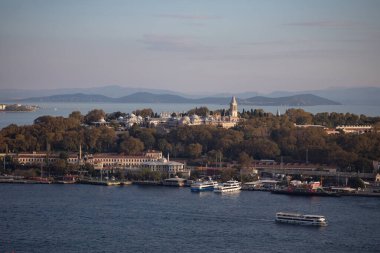 İstanbul, Türkiye - 6 Ekim 2025: Seraglio Point 'teki (Sarayburnu) genişleyen Topkapı Sarayı kompleksi, denizde kayıklar ve puslu arka planda Prensesler adaları ile birlikte uzak bir mesafeden görülüyor.
