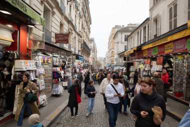 Paris, Fransa - 16 Kasım 2025: Turistler ve yerliler, hediyelik eşya satan küçük dükkanlarla dolu kalabalık bir caddede yürüyorlar.