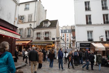 Paris, Fransa - 16 Kasım 2025: Montmartre 'nin işlek tarihi çeyreğindeki dükkanlar ve restoranların önünden geçen ve gezen insanlar.