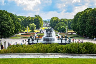 Oslo, Norveç - 16 Temmuz 2025: Yükselen manzara, bereketli yeşil ağaçlar ve Frogner Park 'taki gül bahçeleriyle çevrili devasa Vigeland Çeşmesini gösteriyor..