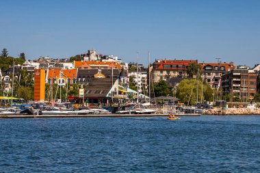 Oslo, Norveç - 17 Temmuz 2025: Sürat tekneleri ve yelkenliler Frognerkilen Körfezi 'nde bir rıhtıma demirlediler ve arka planda Skillebekk mahallesinin renkli tarihi mimarisi yer aldı..