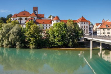 Fussen, Almanya - 19 Eylül 2023: St. Mang Benedikt Manastırı manzarası Fussen, Bavyera 'daki Theresienbrucke köprüsü ile Lech Nehri' ne yansıdı..