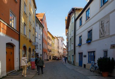 Fussen, Almanya - 19 Eylül 2023: Turistler, Fussen 'in Altstadt ilçesindeki renkli tarihi binalar ve geleneksel dükkanlarla dolu dar bir kaldırım taşı caddesi boyunca yürüyorlar.