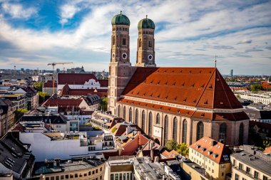 Münih, Almanya - 21 Eylül 2023: Yüksek bir manzara, Bavyera 'da dramatik bir gökyüzü altında eski şehrin ikonik Frauenkirche katedralini ve kırmızı kiremitli çatılarını gösteriyor.