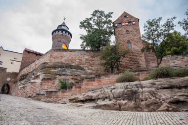 Nuremberg, Almanya - 22 Eylül 2023: İmparatorluk Kalesi 'nin devasa taş tahkimatı ve Sinwell Kulesi Nuremberg' deki kaldırım taşı yolu boyunca doğal kaya oluşumlarının üzerinde yer alır..
